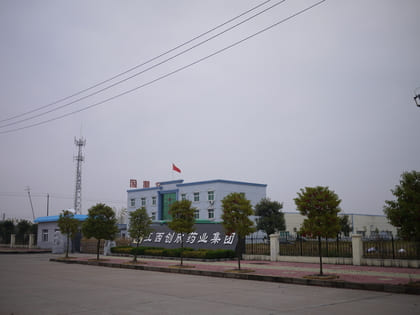 Industrial building with trees and a flag outside.